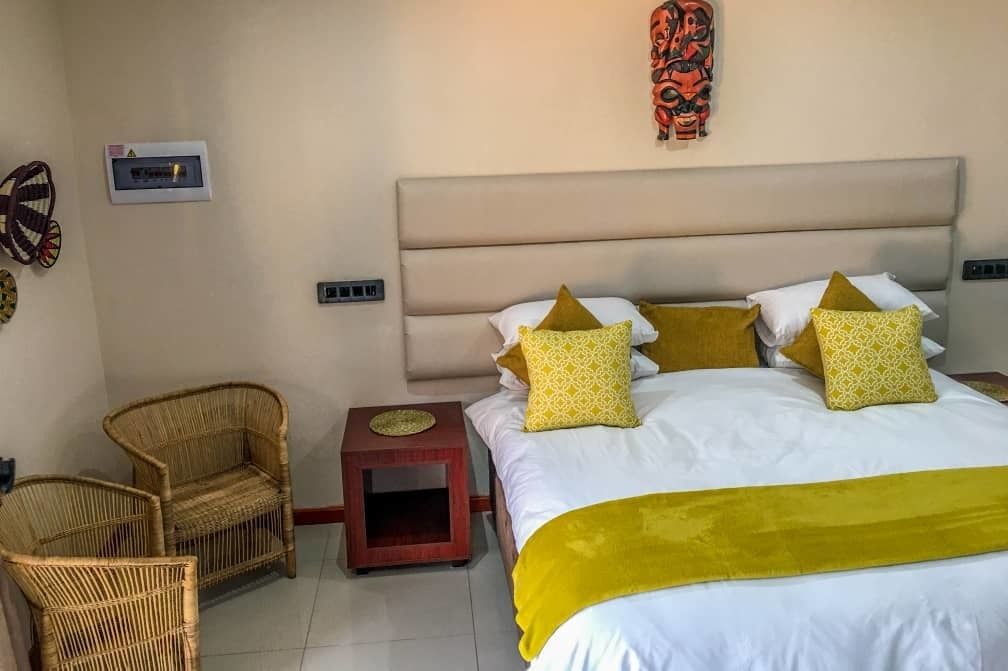 A bedroom with a bed, two nightstands, a chair, and a wall-mounted decorative piece.