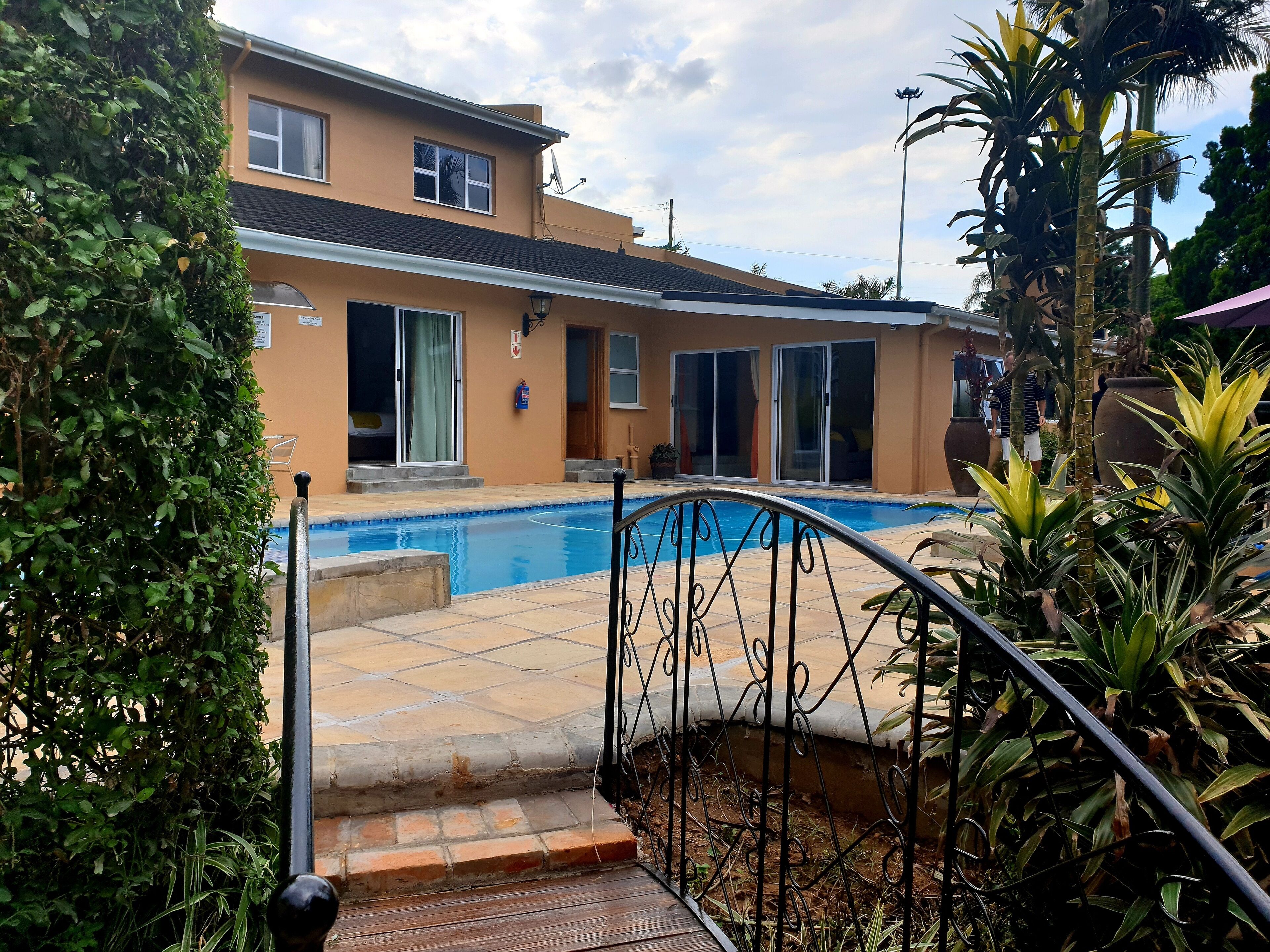 Un immobile residenziale con piscina, una scala che conduce a un patio e una casa ampia con porte scorrevoli in vetro.