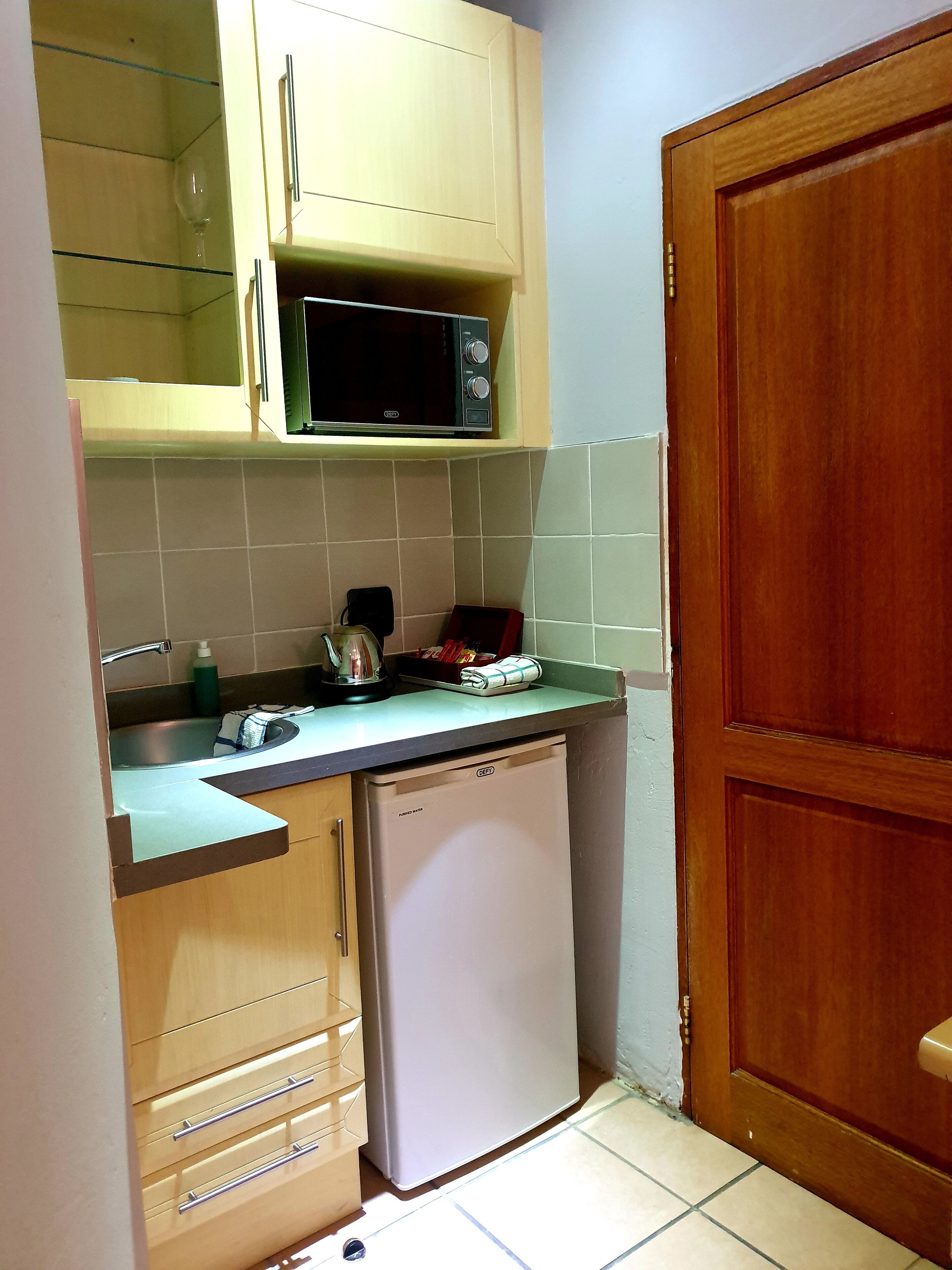 A compact kitchen with a microwave, sink, and a small refrigerator.