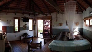 Une cabane rustique avec un plafond en bois, un lit à baldaquin, une table en bois et une chaise.