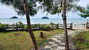 A paved pathway leading to a beach with palm trees and a wooden fence. - Sea Smile Resort (Prachuap Khiri Khan)