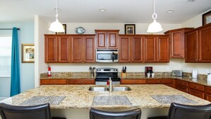 A kitchen with granite countertops, wooden cabinets, a stainless steel sink, and a built-in microwave. - Paradise Palms #3 - 6 Bed 5 Baths Villa (Kissimmee)