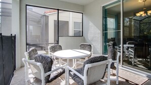 A patio with a round table and six chairs, a sliding glass door, and a view of the interior. - Paradise Palms #3 - 6 Bed 5 Baths Villa (Kissimmee)