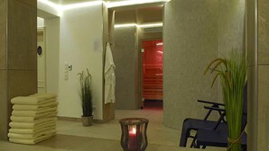 A hotel lobby with a stack of towels, a potted plant, a candle, and a seating area. - Hotel am Südwäldchen (Sylt)