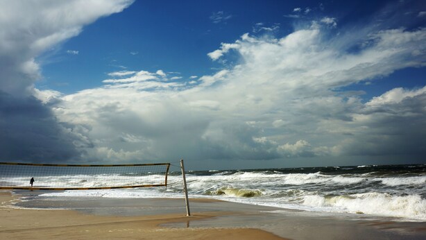 A beach volleyball net on a sandy beach with the ocean in the background. - Hotel am Südwäldchen (Sylt)