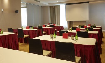 A conference room with tables set for meetings, equipped with chairs, tables, and presentation screens.