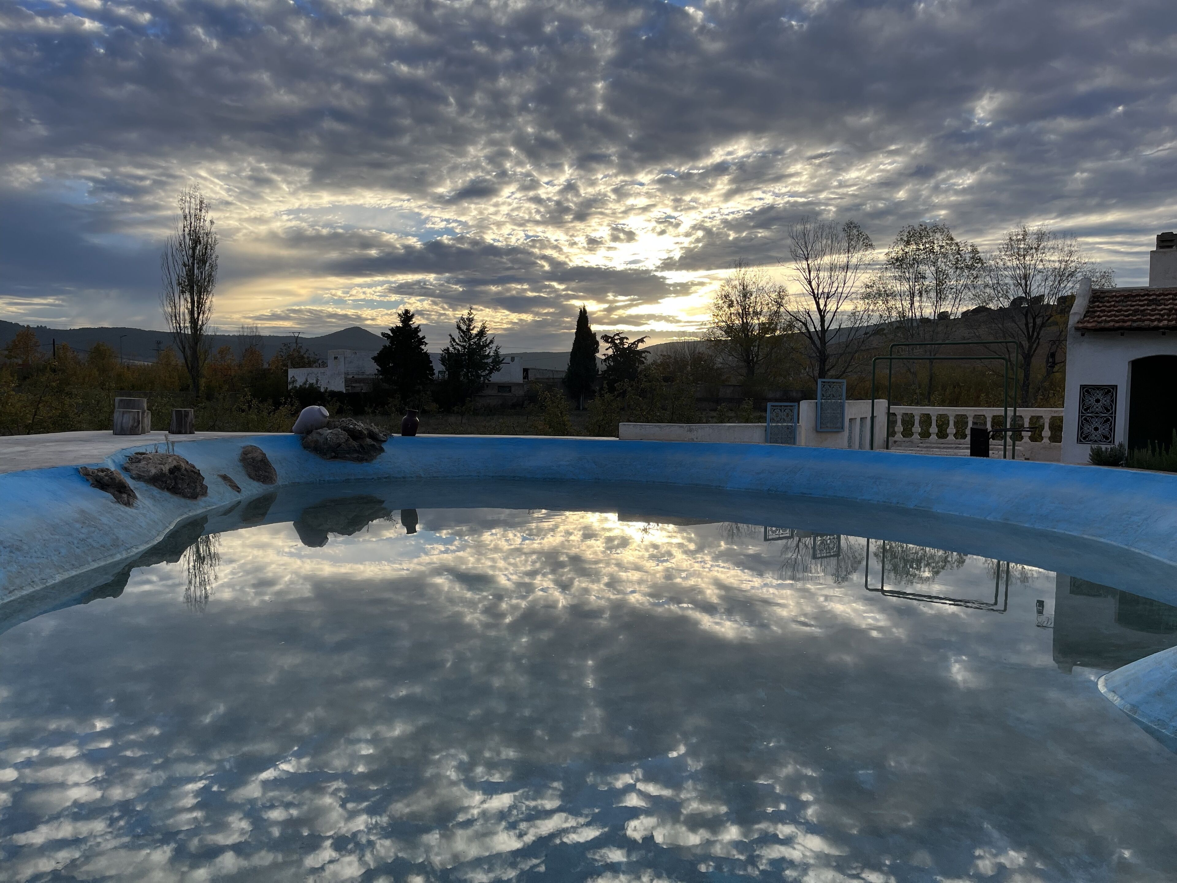 Piscina com reflexo nítido do céu e da paisagem ao redor.