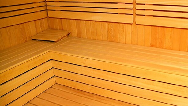 Un sauna en bois avec des bancs et une banquette.