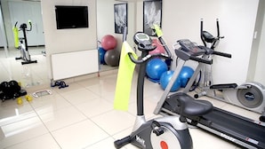 Une salle de sport équipée de matériel d’exercice, notamment des tapis de course et des vélos d’appartement, ainsi que des ballons d’exercice.