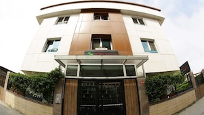 Un bâtiment moderne à la façade incurvée, doté d’une entrée centrale avec un portail noir et d’une enseigne au-dessus de l’entrée.