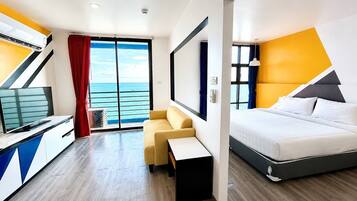 Habitación de hotel con cama, escritorio, silla, televisor y vista al mar.