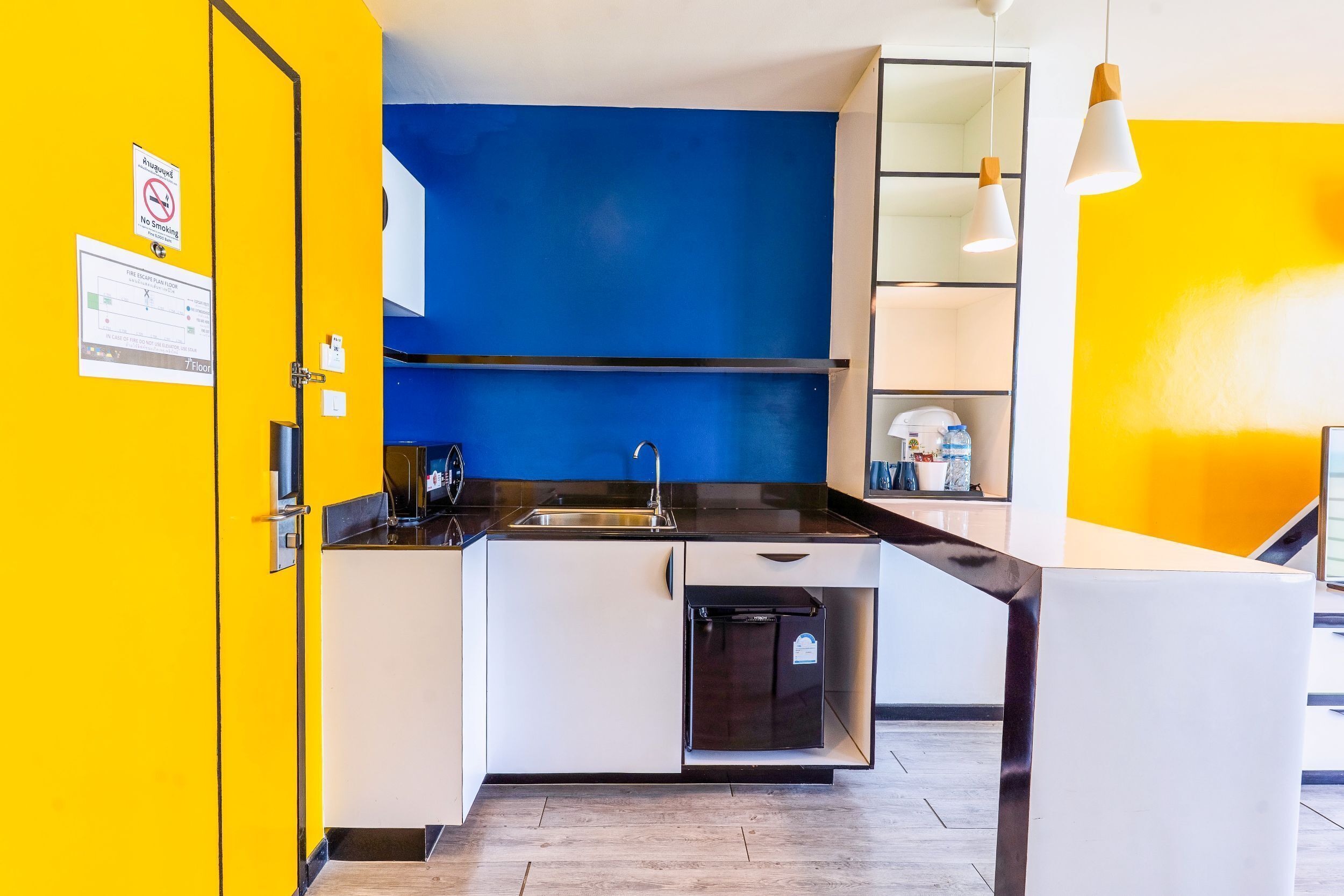 Een moderne keuken met een gele deur, een blauwe accentmuur en een roestvrijstalen spoelbak.