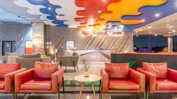 Un vestíbulo moderno con sillones de cuero rojo, una recepción y un diseño de techo colorido.