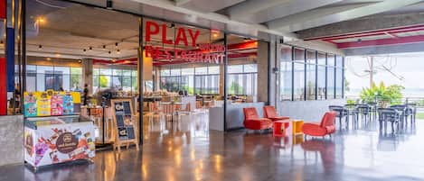 Un restaurante moderno con área de juegos, ventanas amplias y diferentes opciones de asientos.