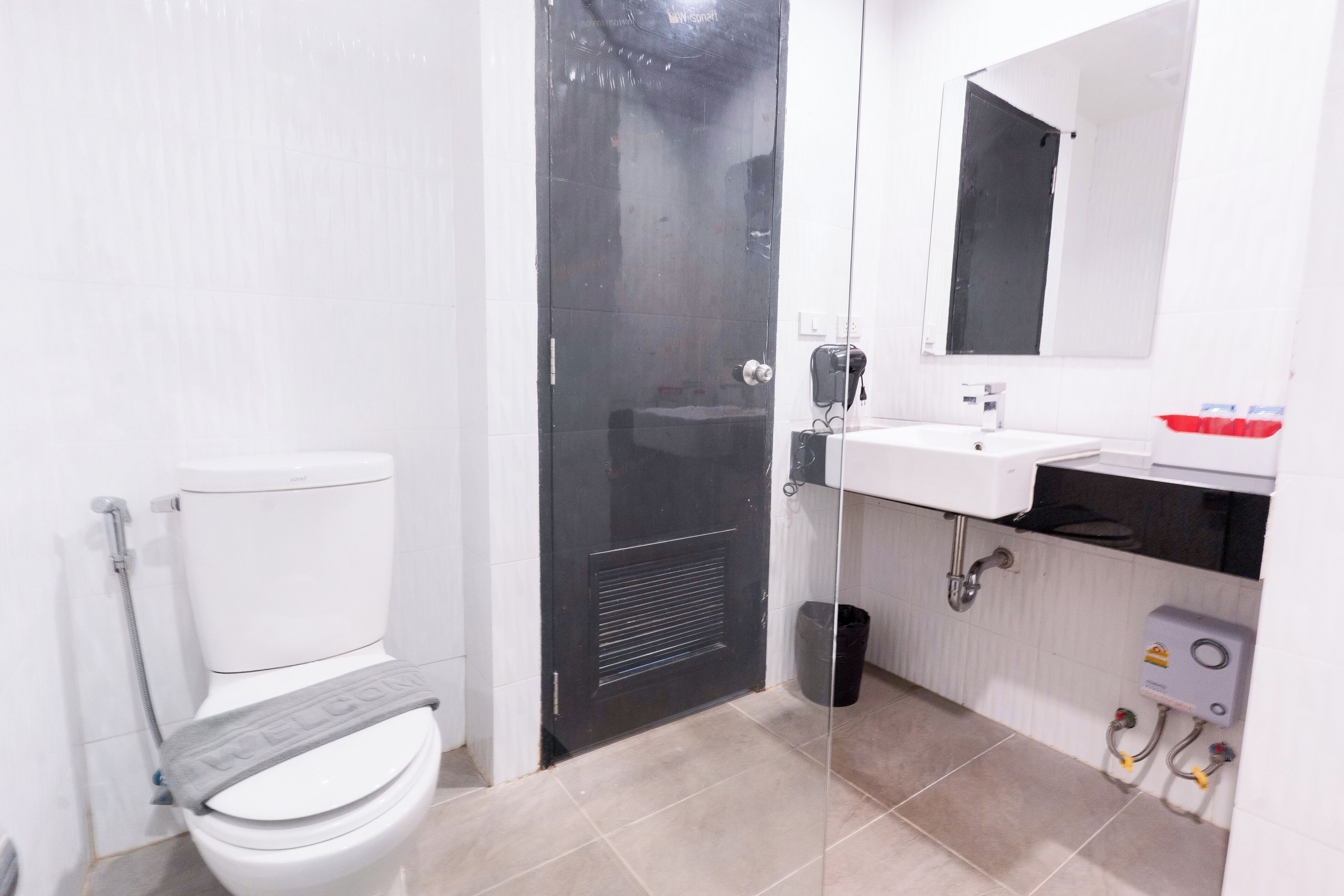 Un baño con inodoro, cabina de ducha y lavamanos con espejo.