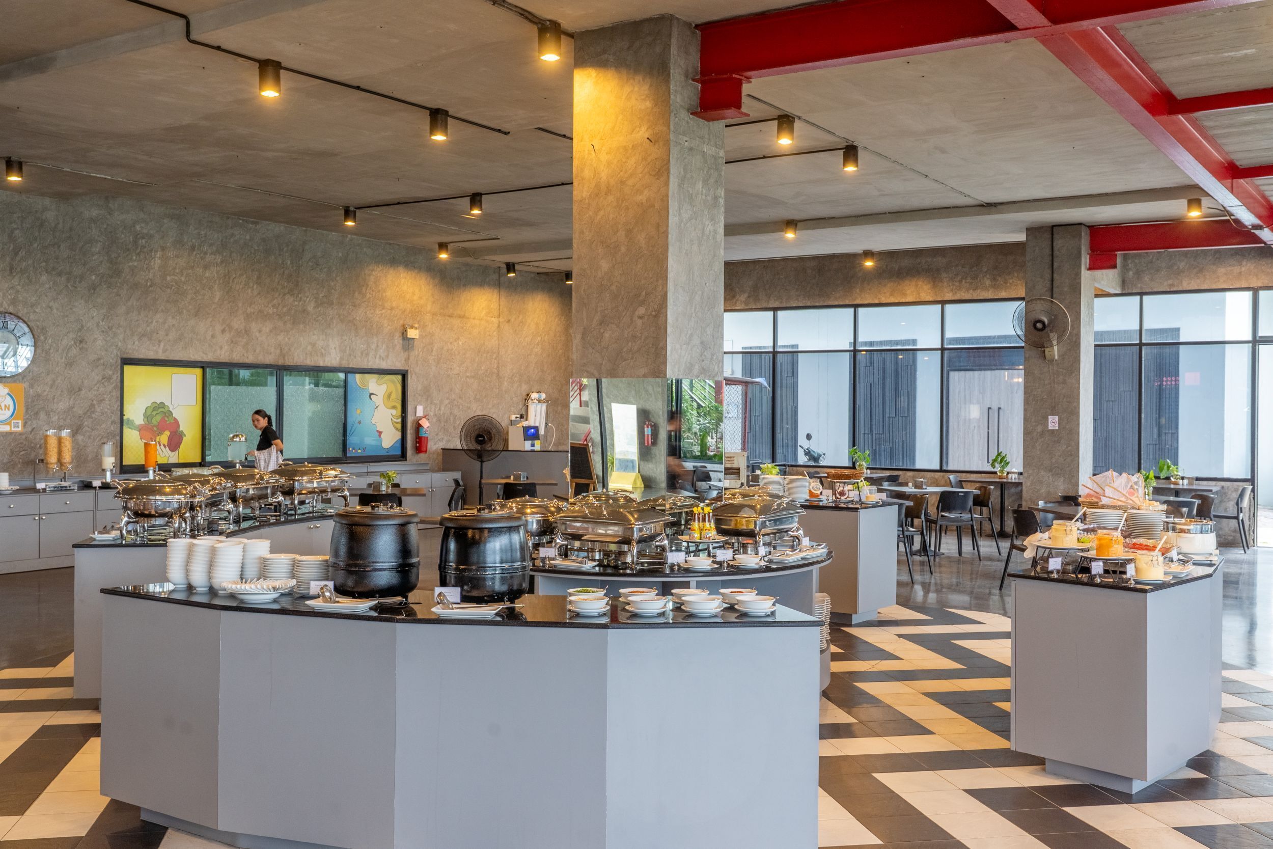 Un moderno comedor de desayuno tipo buffet con varias estaciones de comida, un reloj y obras de arte en las paredes.