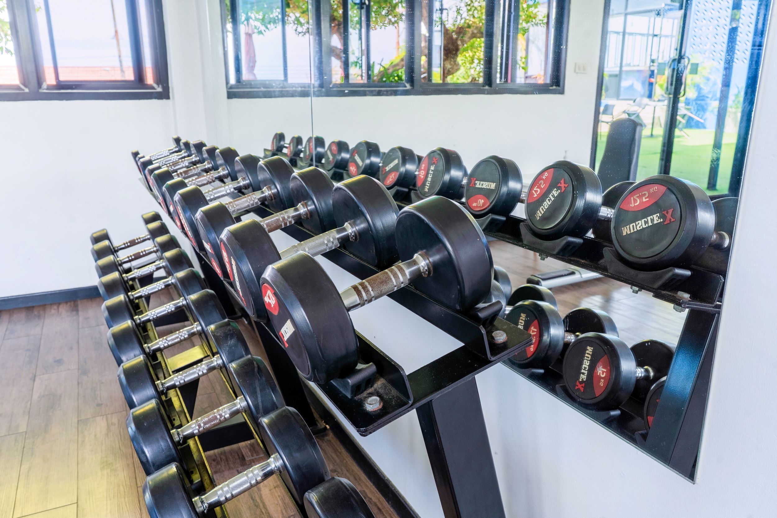 A gym with rows of dumbbells on racks.