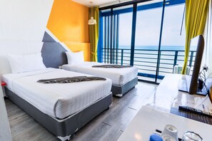 Habitación de hotel con dos camas, un escritorio, una computadora y vista al mar.