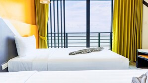 Ein Hotelzimmer mit einem Bett, einem Fenster mit Vorhängen, einem Nachttisch und einer Lampe.