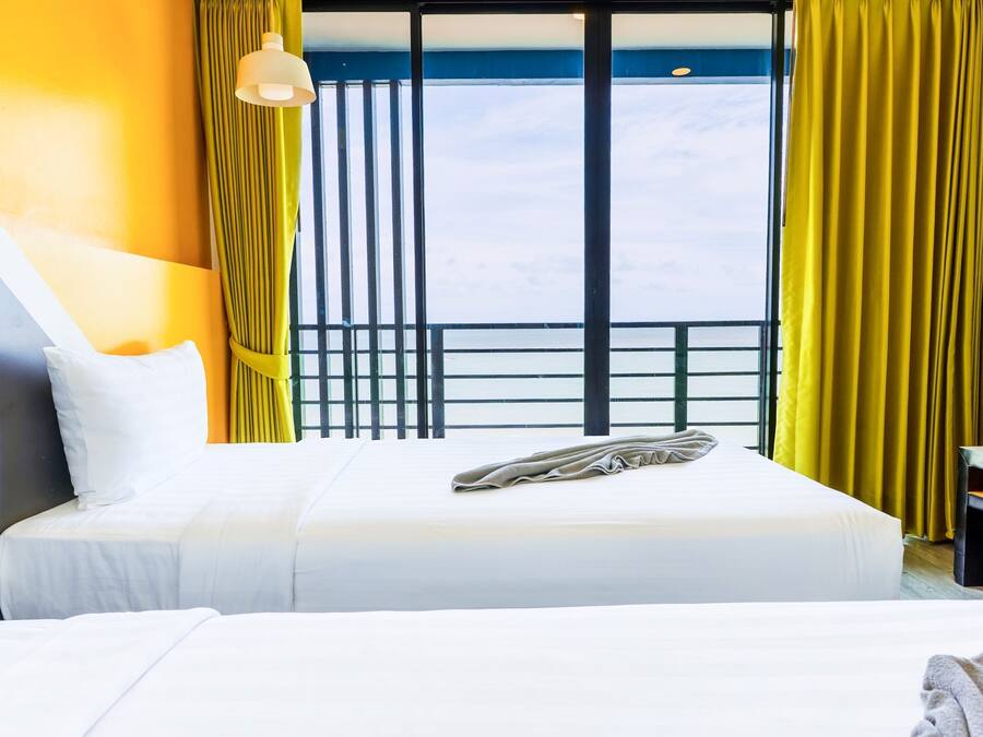 Una habitación de hotel con una cama, una ventana con cortinas, una mesita de noche y una lámpara.