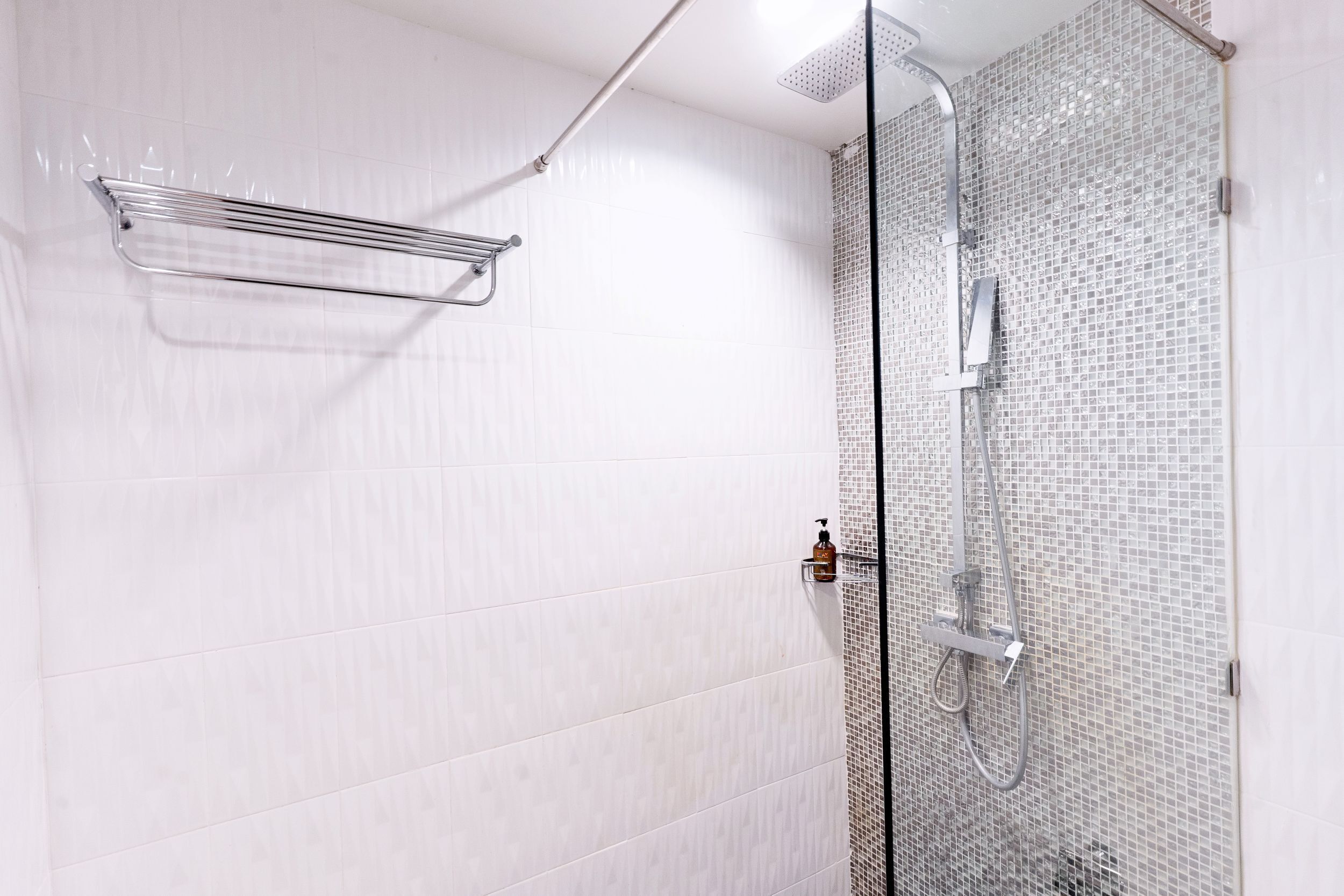A modern shower area with a glass door, a chrome towel rack, and a showerhead.