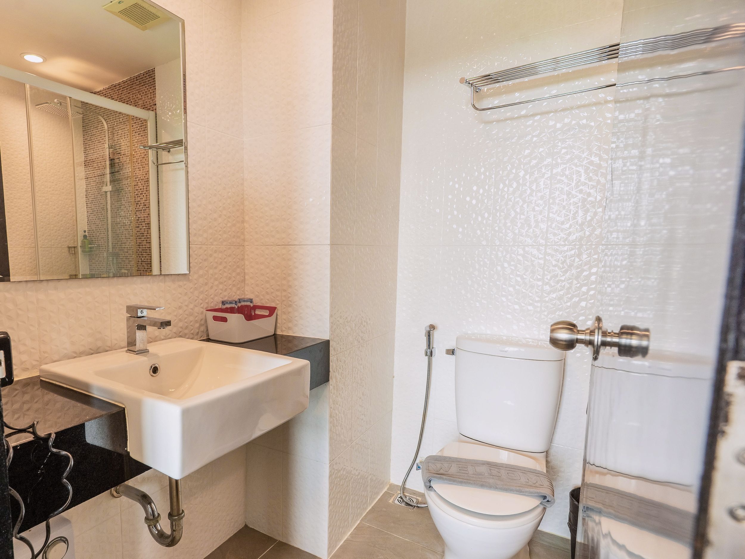 A modern bathroom with a white sink, a toilet, and a shower area.