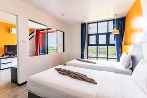 Habitación de hotel con dos camas, televisión y ventana con cortinas.