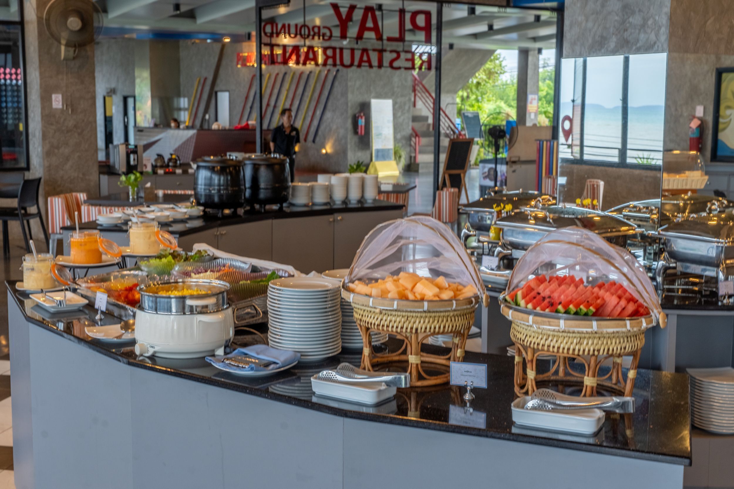 A buffet area with various food items and a view of the restaurant in the background.