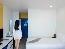 Habitación de hotel con una cama, un escritorio con una silla, un espejo y una puerta azul.