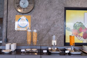 A breakfast bar with cereal dispensers, a clock, and a fruit illustration on the wall. - Play Phala Beach Rayong (Ban Chang)