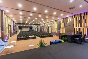 A conference room with rows of chairs, a stage, and a seating area with tables and chairs. - Play Phala Beach Rayong (Ban Chang)