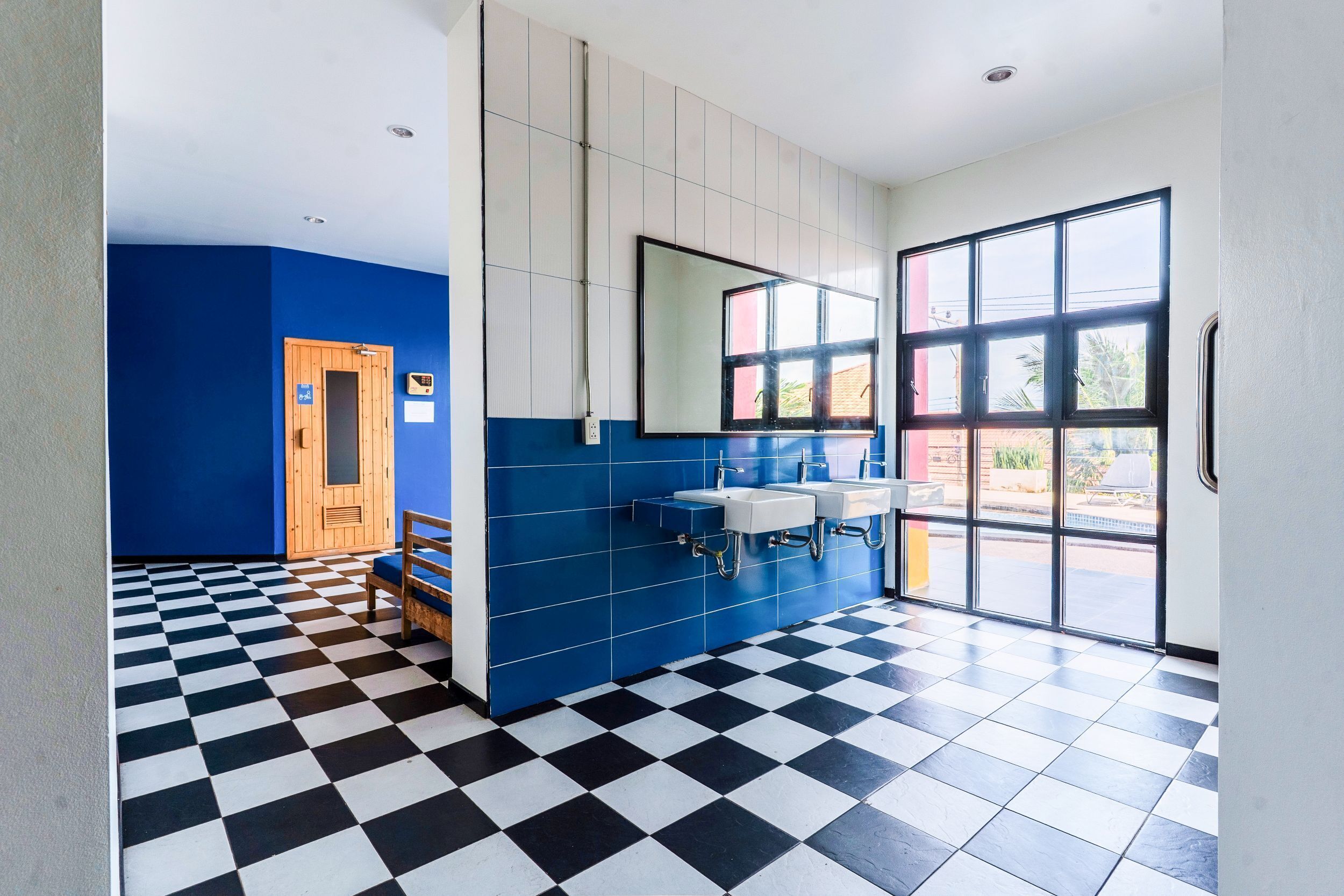Un baño con piso a cuadros, una puerta de madera y un ventanal grande.