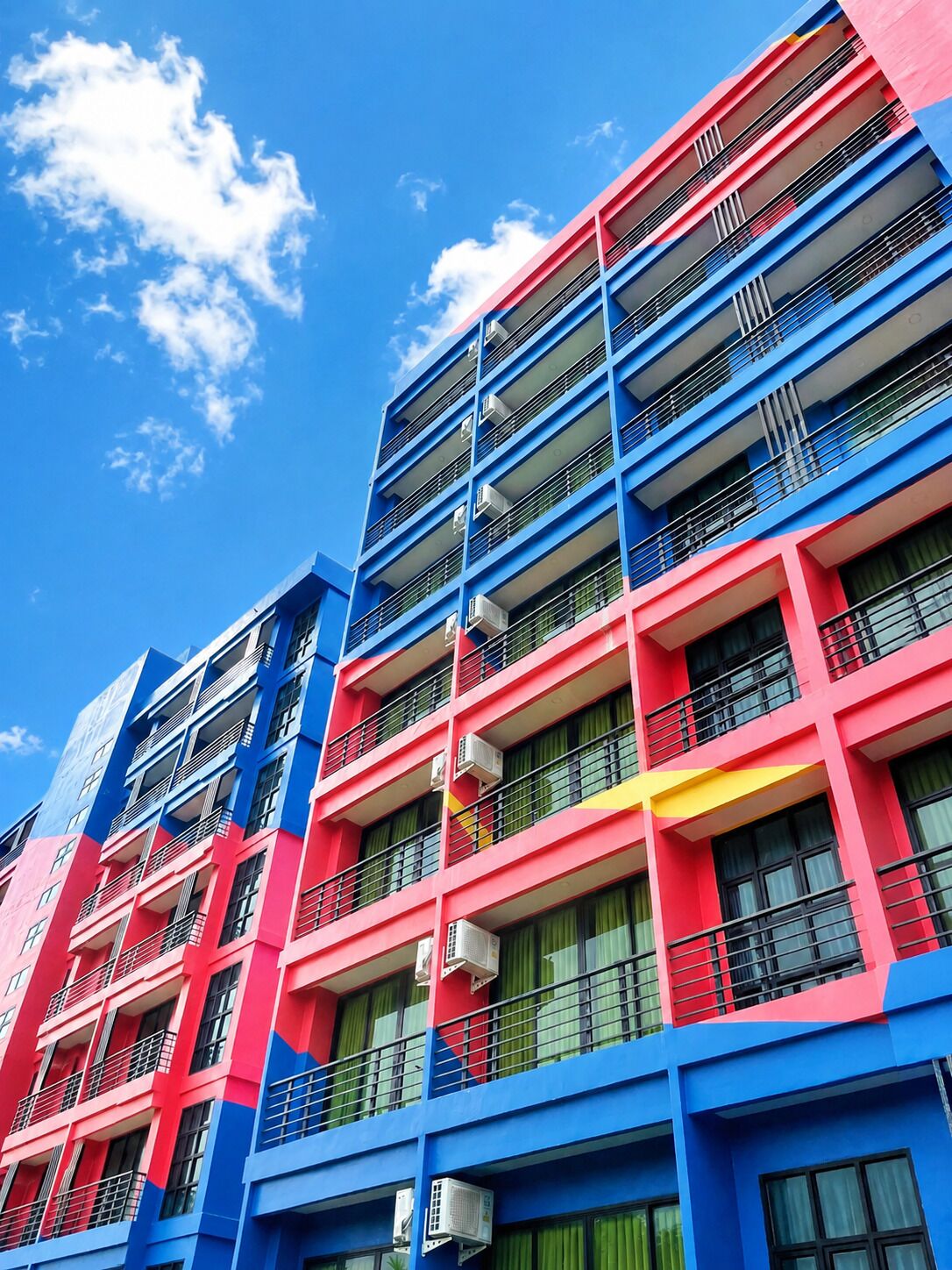 A multi-story building with balconies and air conditioning units.