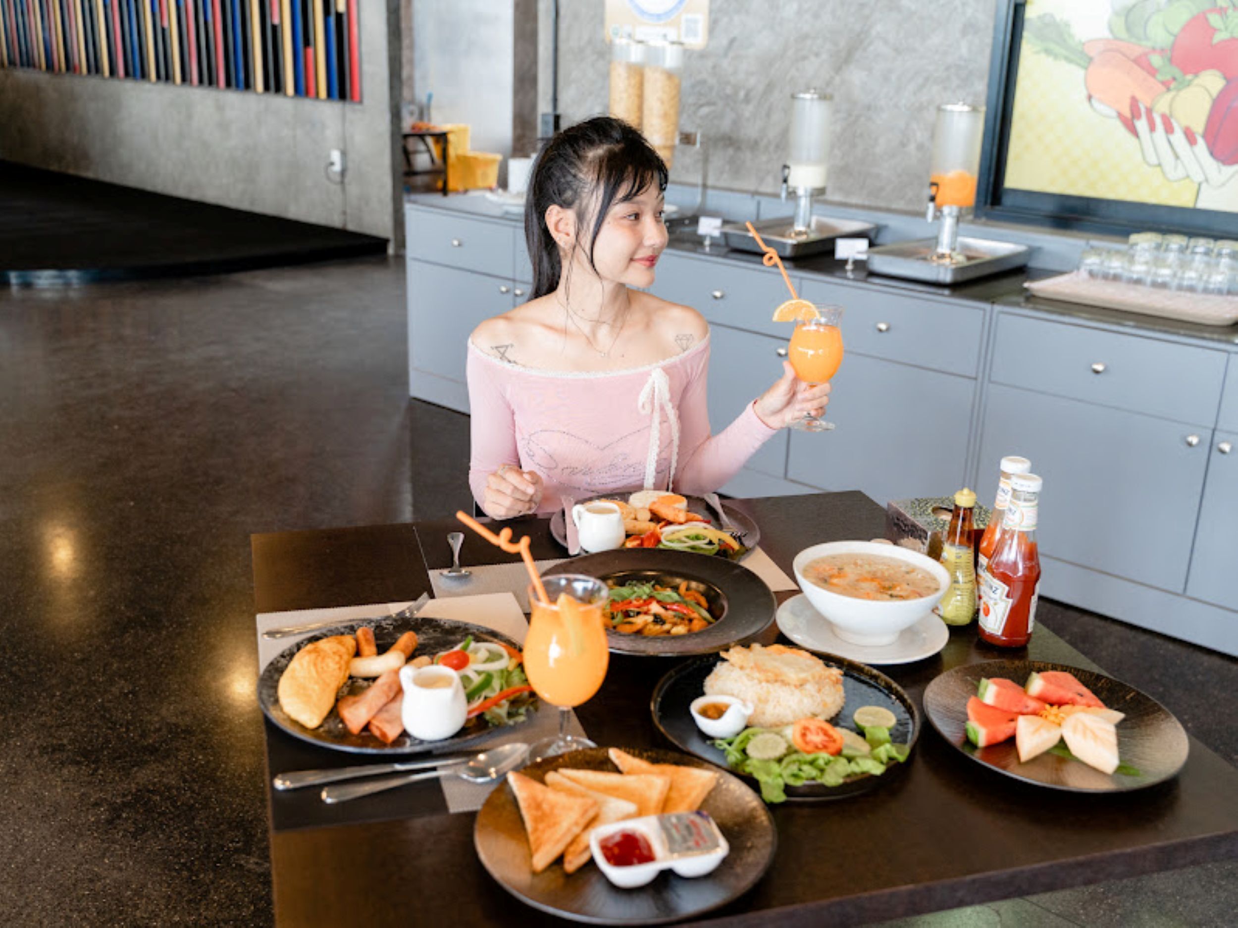 Una persona sentada a una mesa con varios platos, una bebida y aderezos.