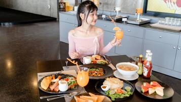 Una persona sentada a una mesa con varios platos, una bebida y aderezos.