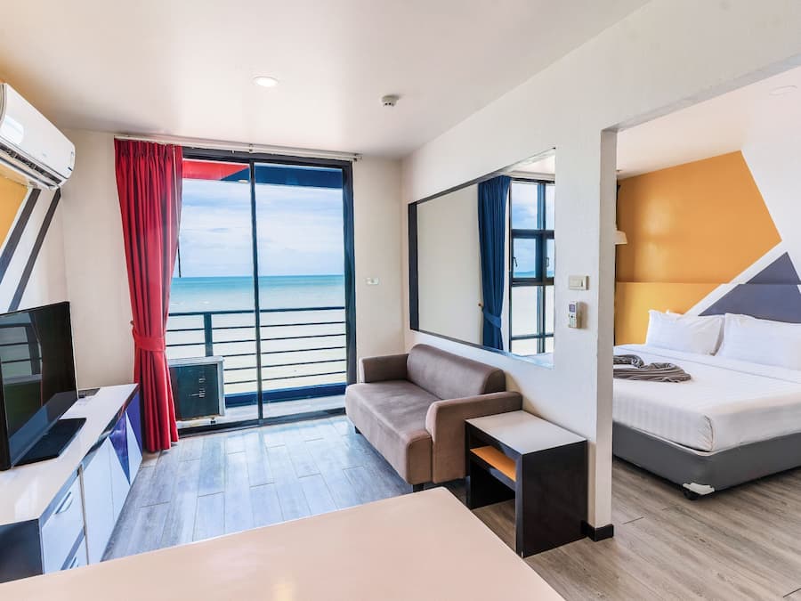Habitación de hotel con cama, escritorio, silla, televisor y vista al mar.