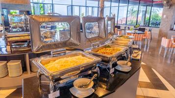 Disposición de bufé con varias estaciones de servicio, incluyendo una estación de arroz y un plato con guarnición verde.