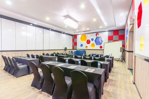 Un salón de conferencias con mesas, sillas, una pizarra y una decoración llamativa en la pared.