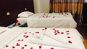 A hotel room with two beds, each covered with white linens and adorned with red rose petals. - Lindi Hotel Baguio (Baguio)