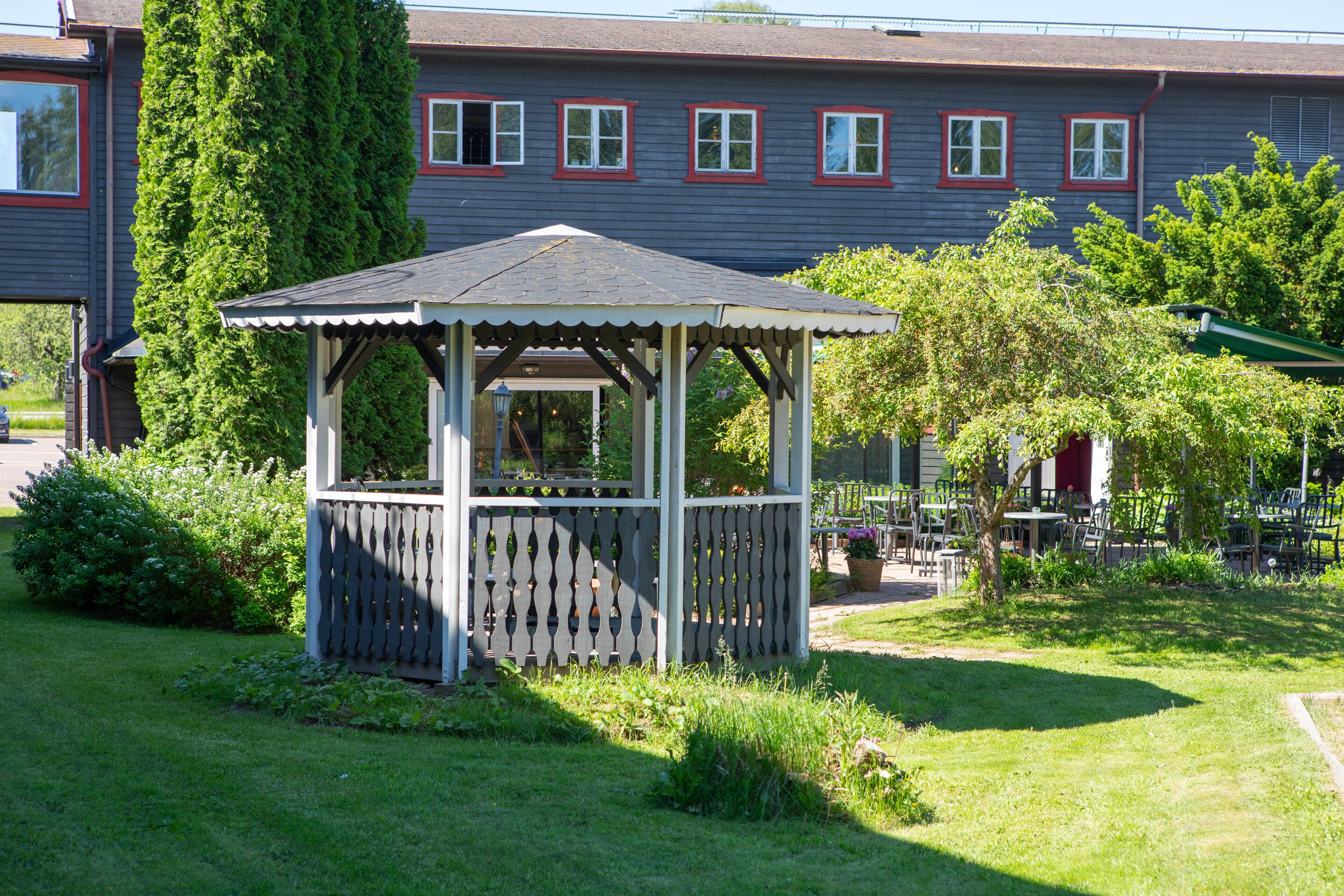 A gazebo in a garden area with a building in the background.