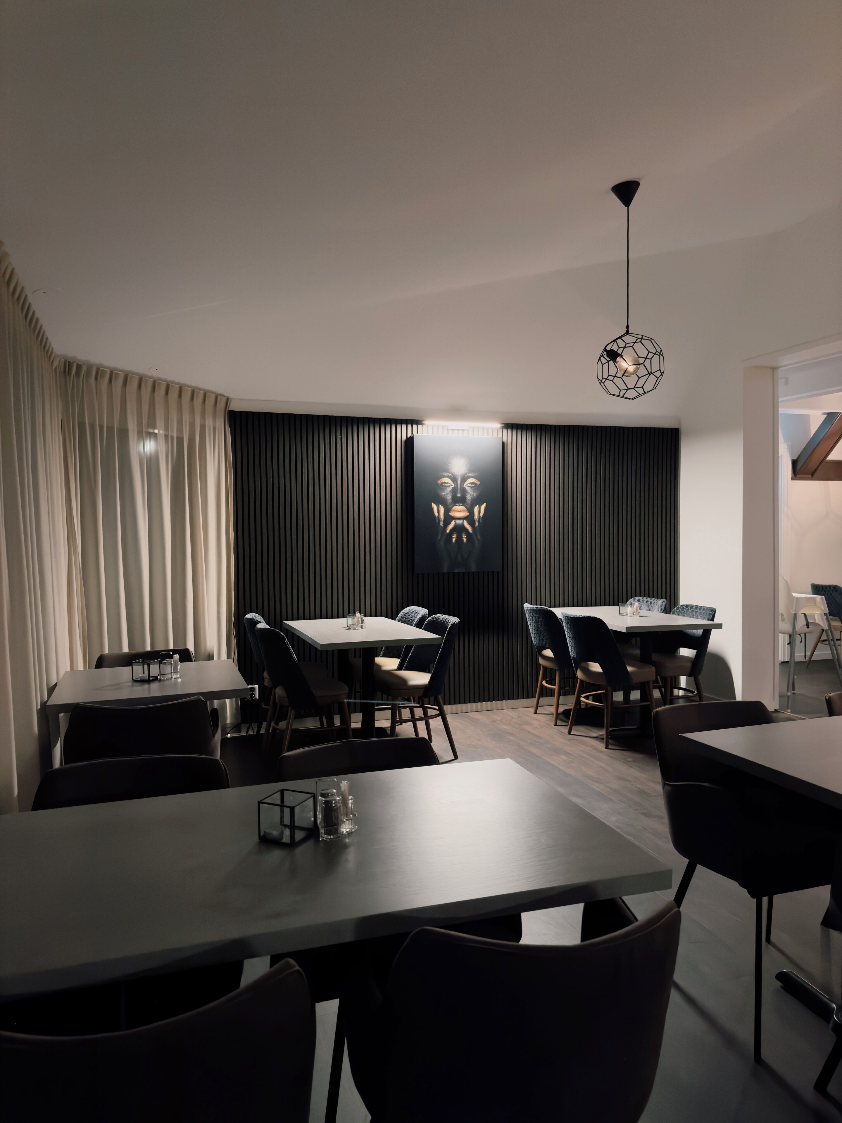 Un comedor moderno con una mesa grande y sillas, un panel decorativo y una lámpara colgante.