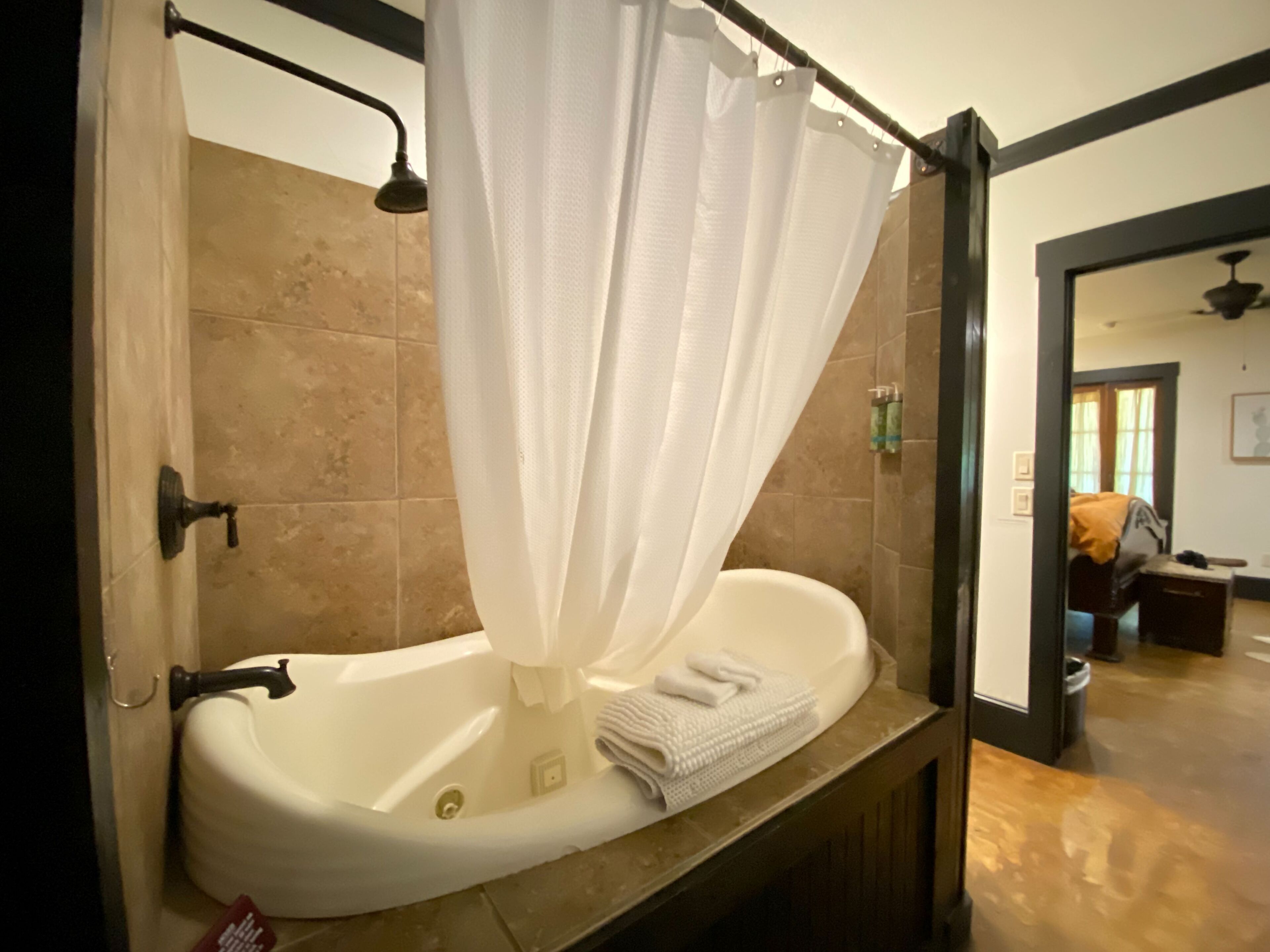 A bathroom with a bathtub, a shower curtain, and a towel on the edge.