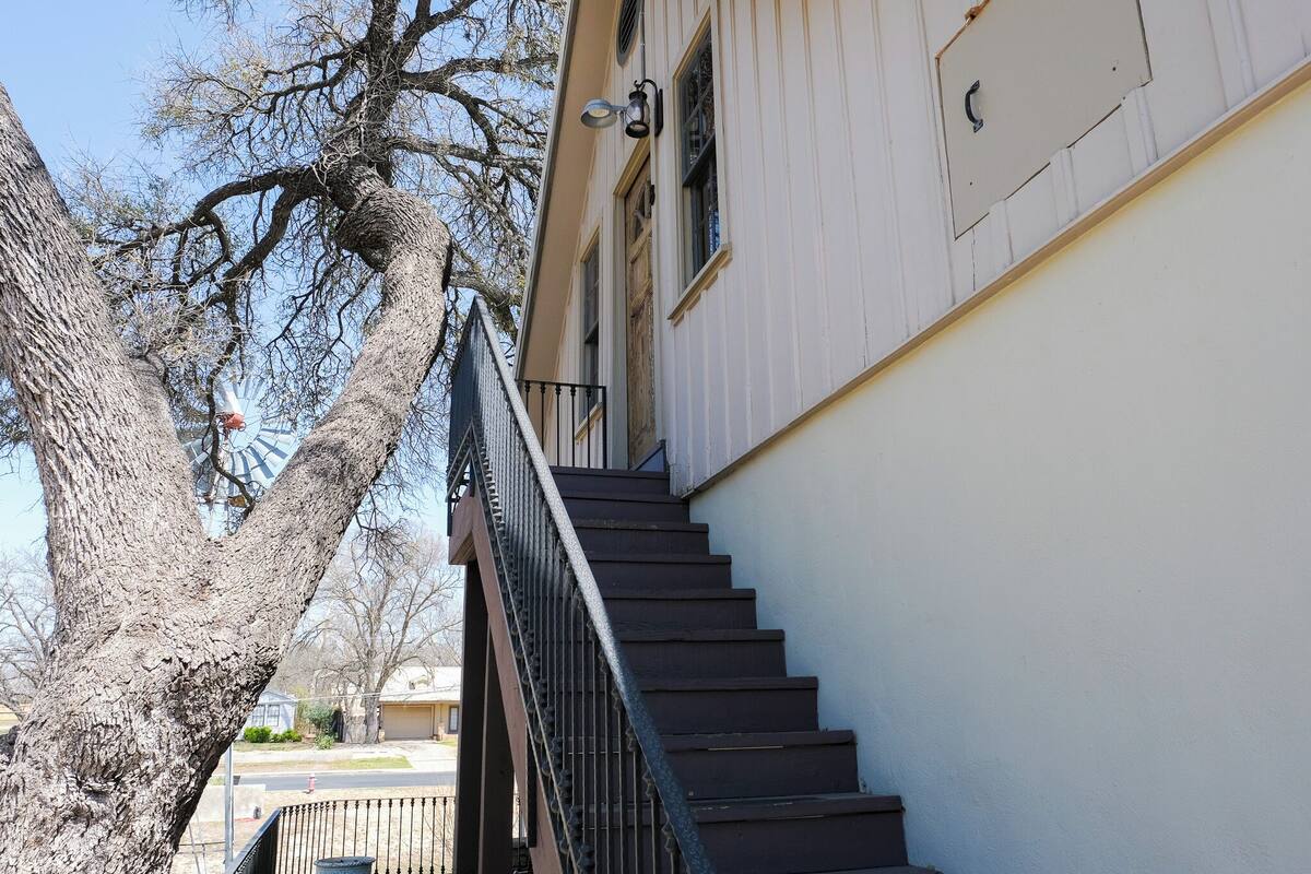 Un escalier menant à un bâtiment à la façade blanche et doté d’une rampe métallique.