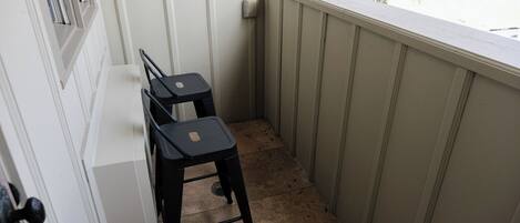 A small balcony with two black chairs and a white table.