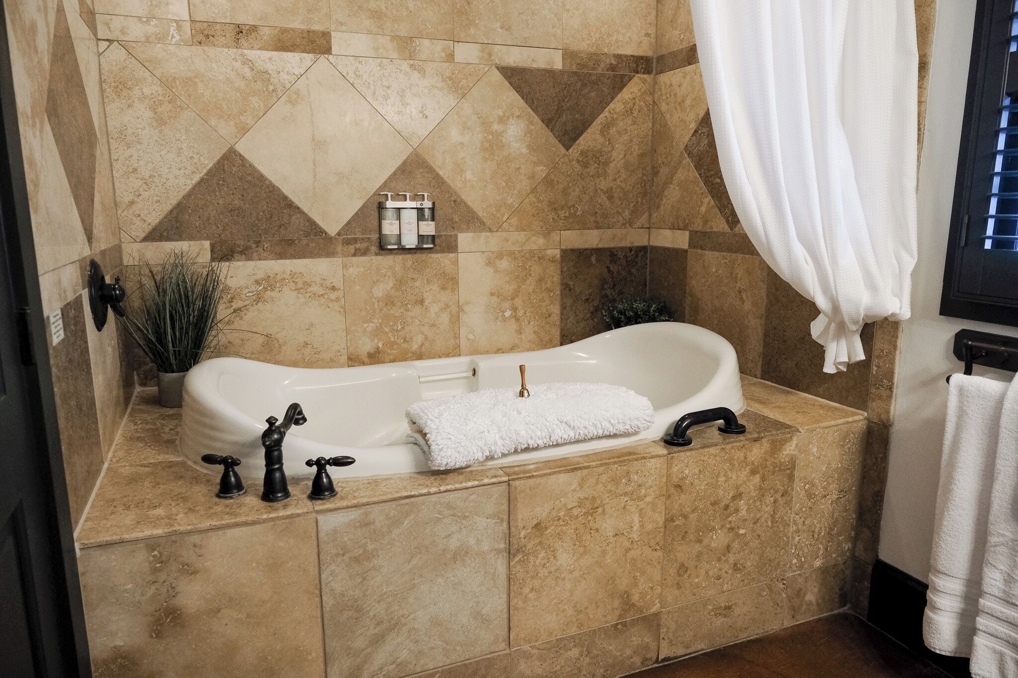 A bathroom with a freestanding bathtub, a towel rack, and a potted plant.