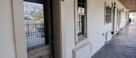 A long corridor with a series of windows and doors, numbered 5, leading to a covered porch area.