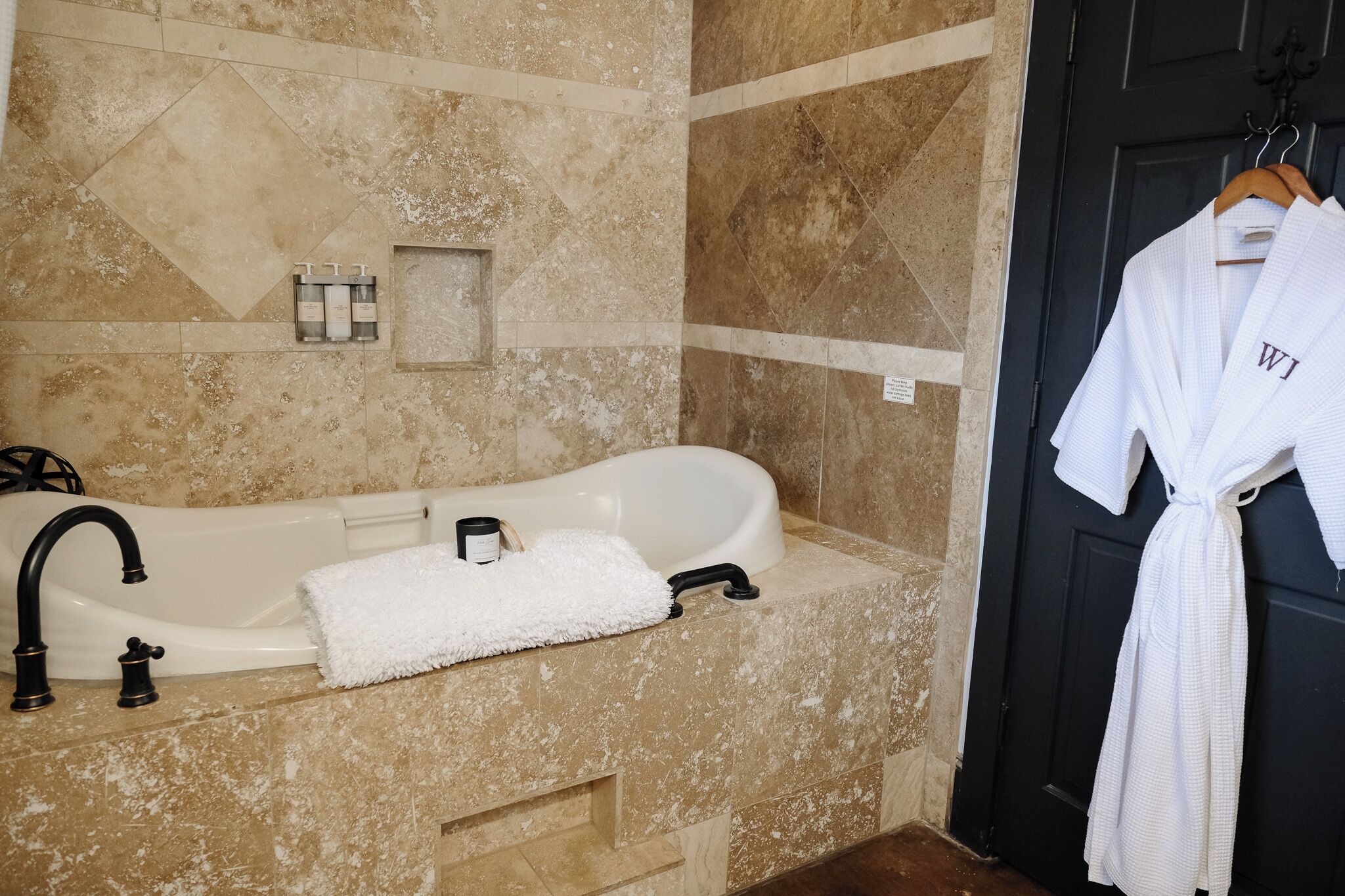 A bathroom with a bathtub, a towel, and a robe hanging on the door.