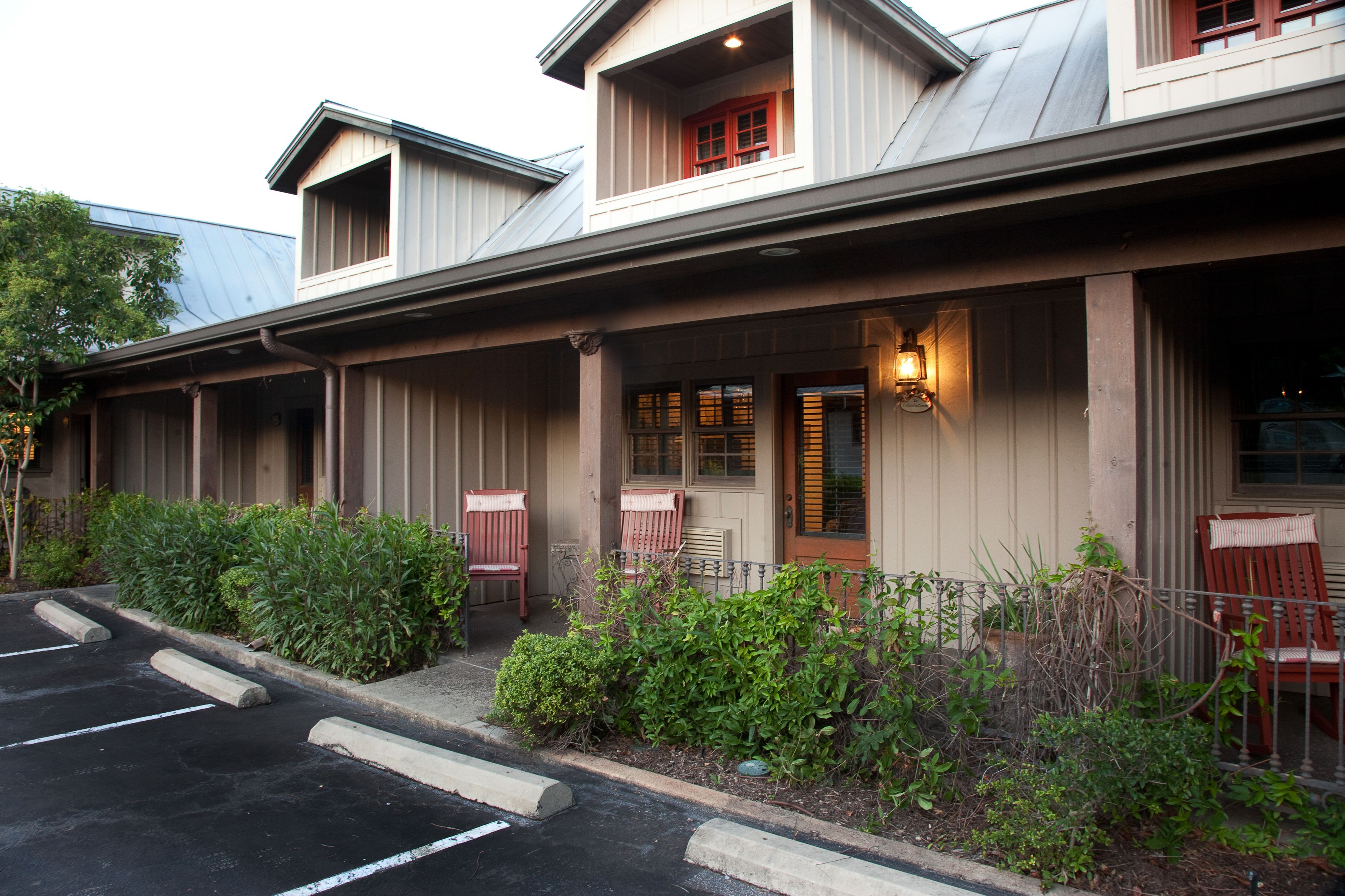 A building with a covered porch, a front door, and a parking lot.