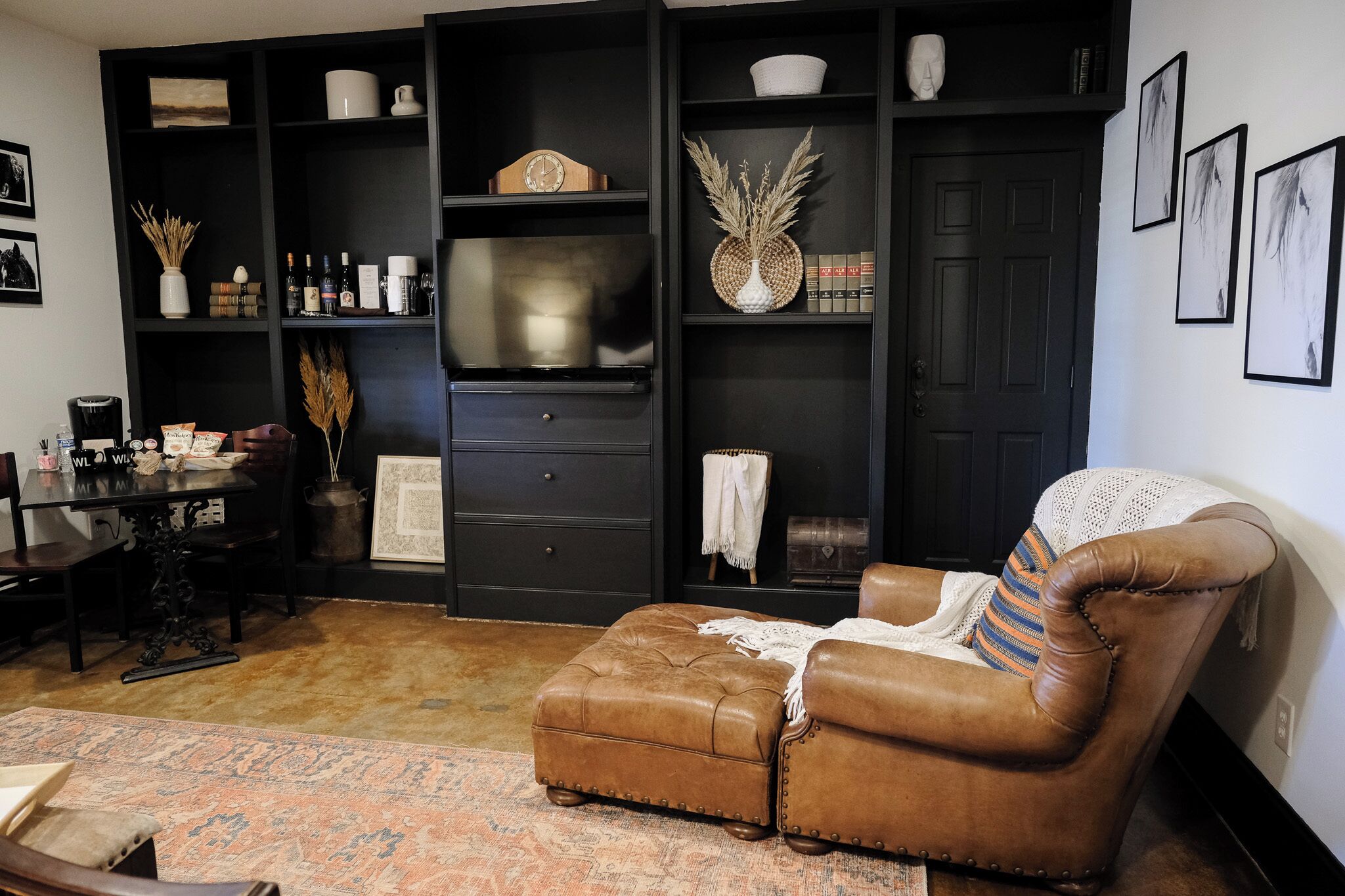 A living room with a brown leather armchair, a coffee table, and a bookshelf filled with books and decorative items.