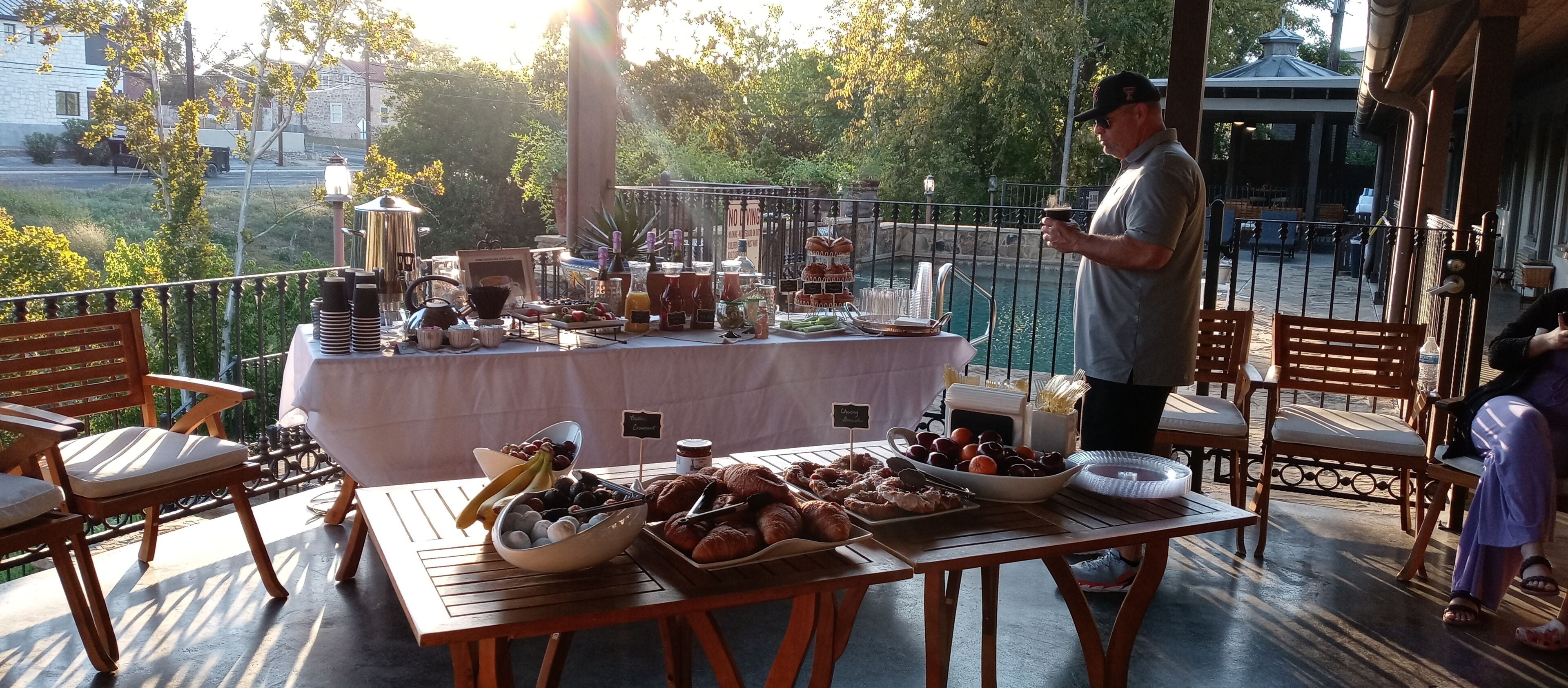 Un bufé de desayuno en un patio al aire libre con mesas, sillas y una variedad de alimentos.